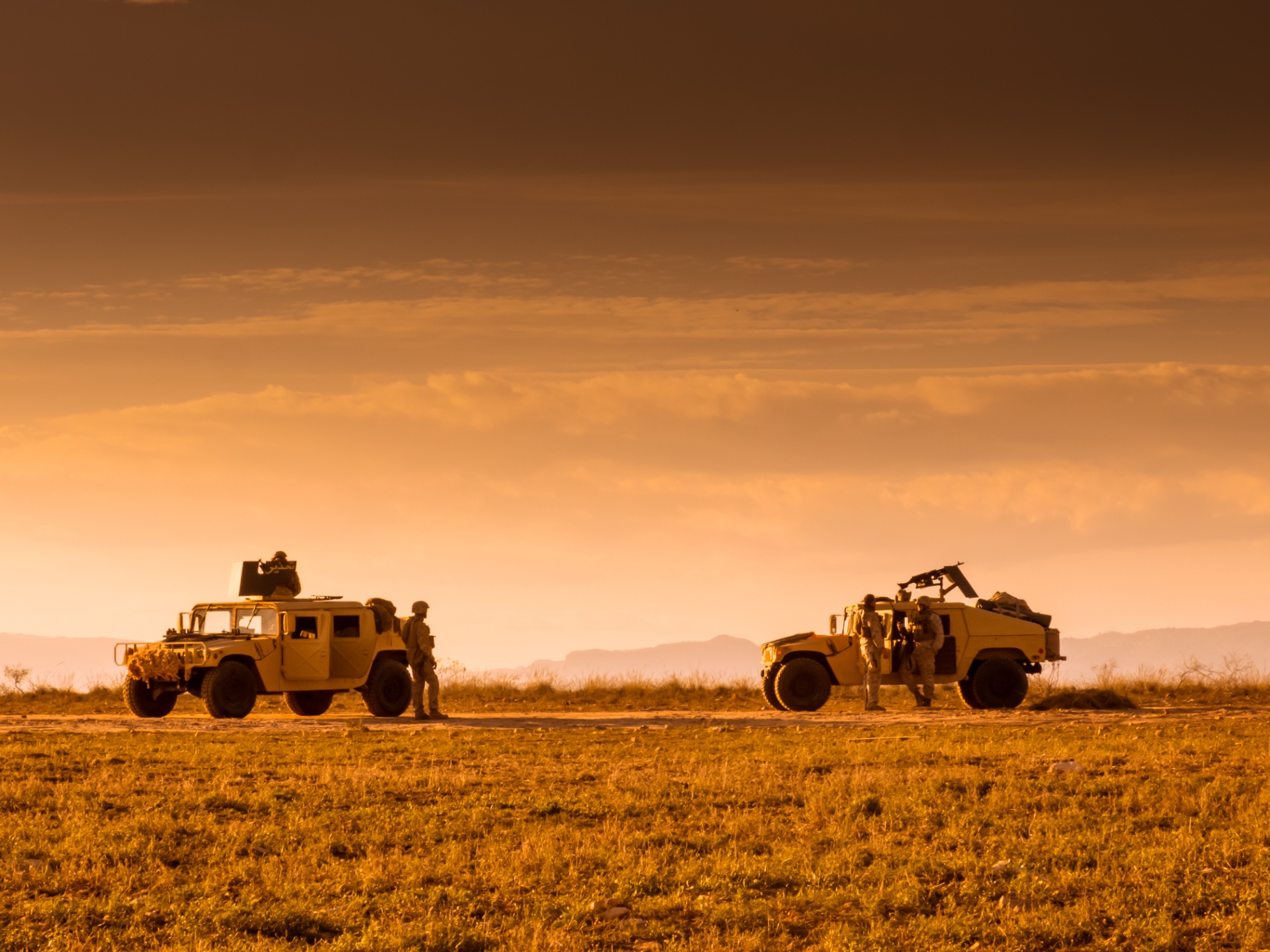 Military vehicles deployed in a desert environment at dusk