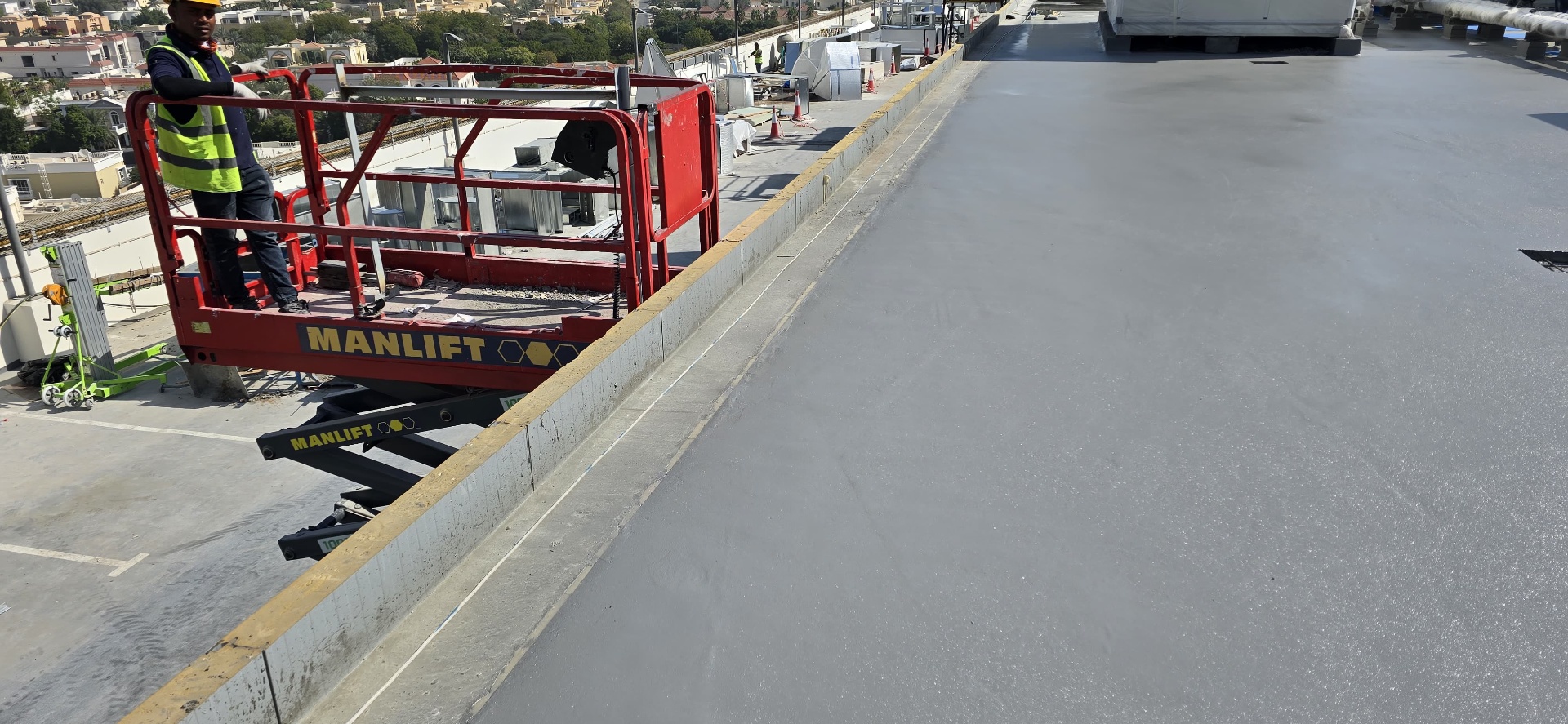 TEXSA operative on a Manlift scissor lift inspecting freshly sprayed polyurea on a rooftop deck