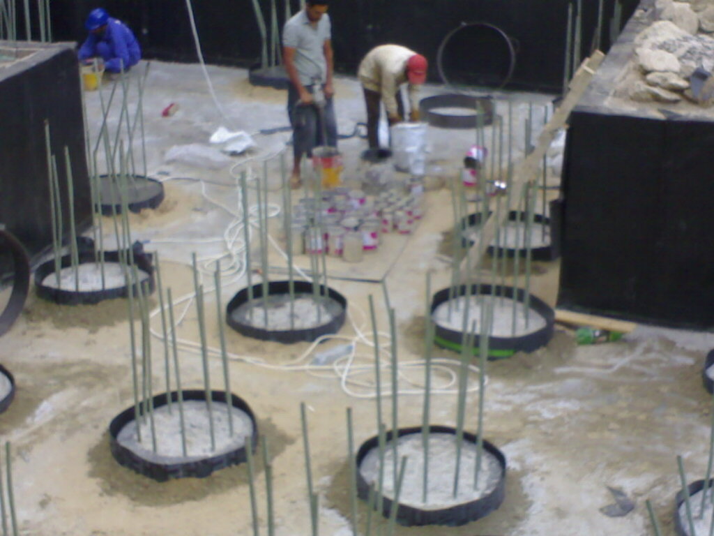 Workers applying primer and sealant around pile head collars