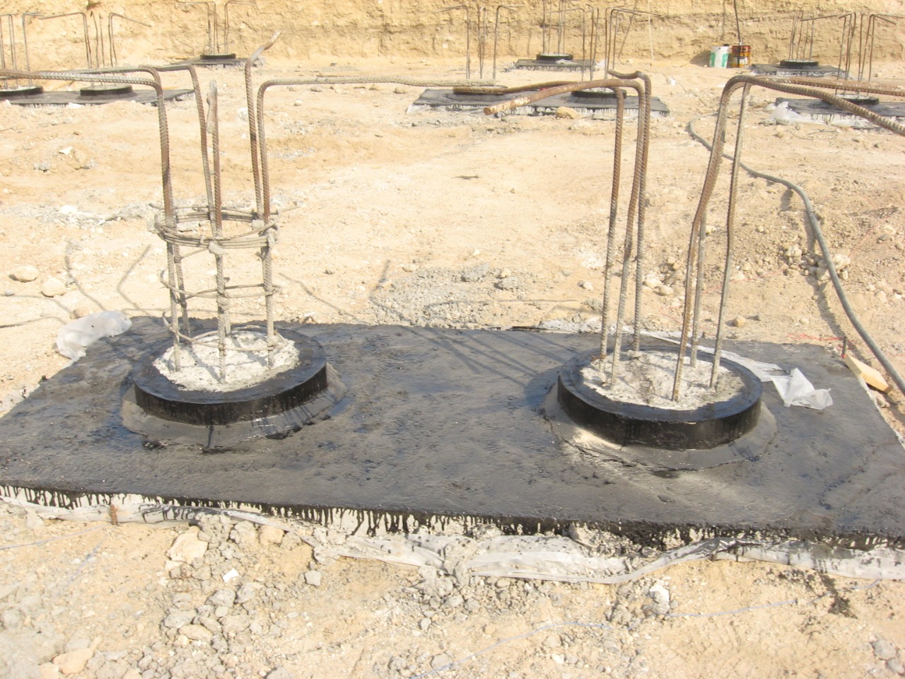 Two pile heads waterproofed with bitumen sheet on sand bed