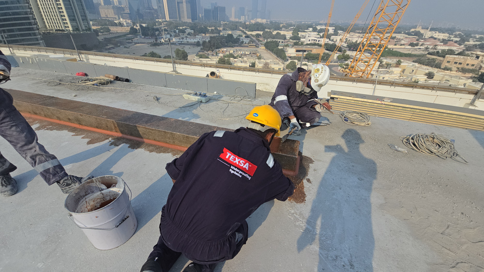 TEXSA crew brushing epoxy primer onto a rooftop upstand