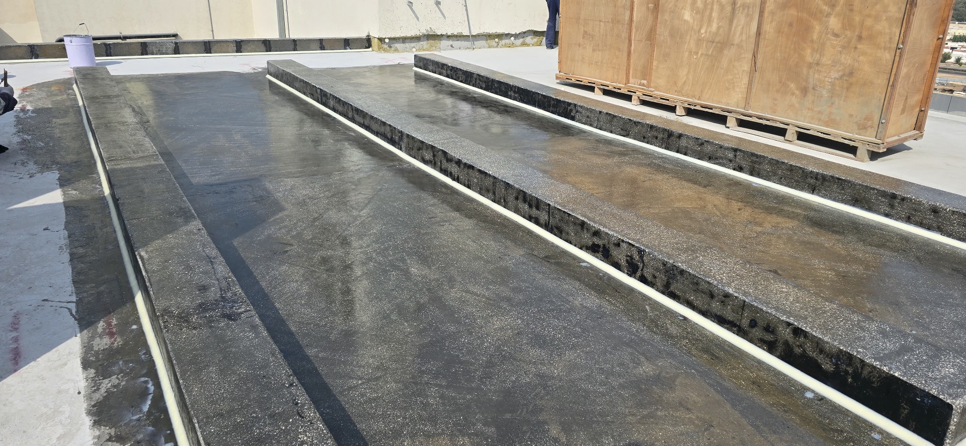 Polyurea-coated upstands on a rooftop showing the seamless black membrane